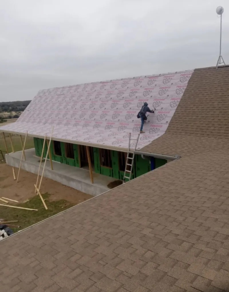 Worker preparing underlayment for a metal roof installation in East Grand Rapids